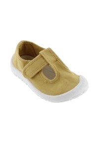 Zapatilla de lona en amarillo mostaza con una correa de velcro, lados abiertos y una suela de goma blanca. Tela texturizada para mayor durabilidad y comodidad.