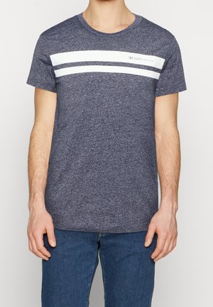 Uomo che indossa una t-shirt blu mélange con due strisce orizzontali bianche e la scritta "DENIM TOM TAILOR", abbinata a dei jeans blu.