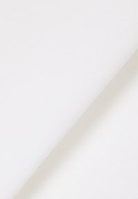 Gros plan sur un tissu blanc plié montrant une texture fine et un motif de tissage diagonal subtil.