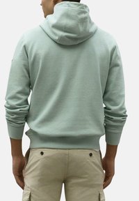 Sudadera verde menta con un bolsillo canguro, capucha con cordón y puños de canalé. Combina con pantalones cargo beige claros. Material de algodón suave.