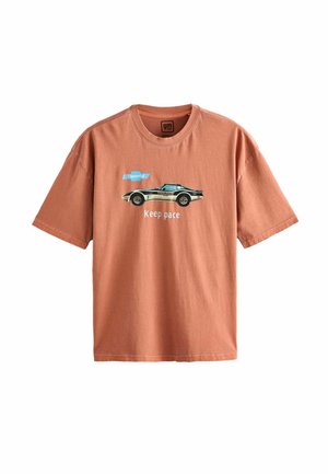 Oranžinė medvilninė marškinėliai su apvalia iškirpte, su juoda retro automobilio grafika ir tekstu "Laikykis tempo" su mėlynu Chevrolet logotipu.