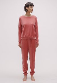 Ensemble de détente côtelé rose comprenant un haut à manches longues à coupe décontractée et un pantalon de jogging assorti, confectionné dans un tissu doux et texturé.