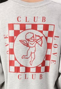 Šedá mikina s červeným grafickým designem zobrazujícím cheruba a kostkovaný vzor. Nápisy zahrnují "CLUB" a "LOVE."