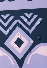 Tejido estampado con formas geométricas en azul oscuro y lavanda. En la superficie hay gotas en forma de lágrima.