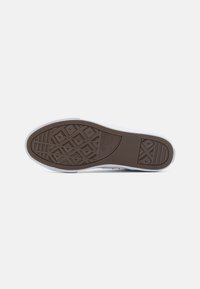 Suela de goma marrón con un patrón de diamante, borde blanco y áreas texturizadas para mayor agarre; diseñada para un estilo de zapatilla casual.