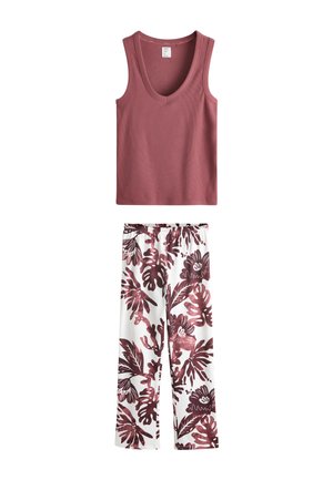 Fiatal nő, rövid sötét hajjal, ujjatlan bordázott mályva felsőt visel, semleges arckifejezéssel világos háttér előtt pózol.