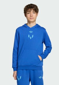 Sudadera azul hecha de un tejido suave, con un bolsillo frontal y acentos de logo en azul claro. El diseño incluye un patrón en V y una capucha con cordones.