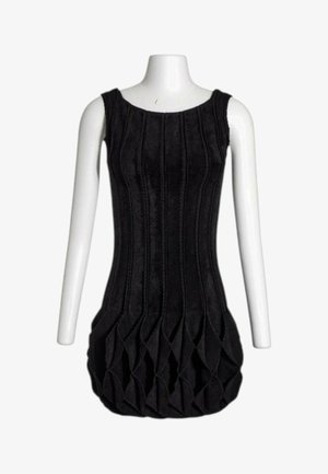 Vestido negro sin mangas con costuras verticales y un dobladillo texturizado, geométrico y estilo burbuja, mostrado en un torso de maniquí blanco.