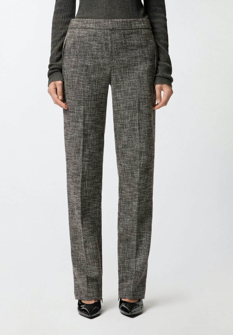 Sive hlače s uzorkom ravnog kroja, s bočnim džepovima i glatkom teksturom, uparene s sjajnim crnim cipelama s oštrim vrhom.