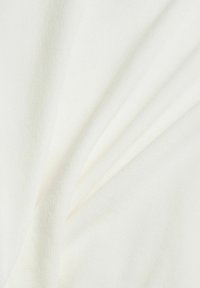 Tissu blanc à la texture douce, présentant des nervures diagonales subtiles et des plis délicats, indiquant un tombé léger et une sensation lisse.