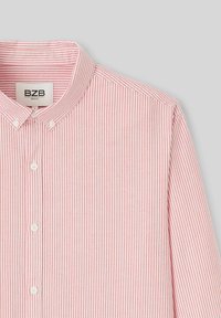 Chemise boutonnée rayée rouge et blanche avec un col, fabriquée en coton doux et avec une texture subtile. L'étiquette indique "Bzb Redlam."