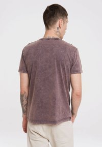 Brown, short-sleeve t-shirt made of soft cotton with a faded, textured appearance and visible stitching along the collar and hem.