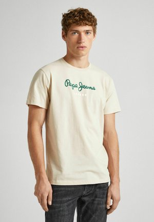 Bež majica od pamuka s ljubičastim 'Pepe Jeans' logotipom u kurzivnom pismu i natpisom 'LONDON' u bijeloj boji, okrugli izrez i kratki rukavi. U kombinaciji s tamnim trapericama.