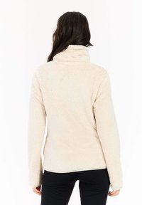 Crème kleurige fleece jas met een hoge kraag en lange mouwen. Zachte textuur en relaxed pasvorm. Zijsplitten aan de zoom bevorderen de bewegingsvrijheid.