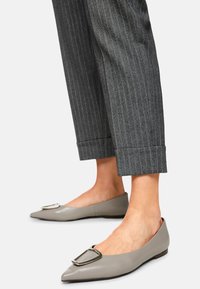 Flat shoes with a pointed toe, made from smooth gray leather. Features a decorative silver buckle on the toe and a minimalistic design.