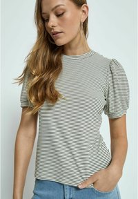Striped short-sleeve top with puffed shoulder design, beige and black stripes, soft fabric, crew neckline, paired with light blue denim shorts.