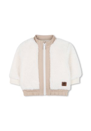 Veste en fausse fourrure crème avec des panneaux en tissu beige. Dotée d'une fermeture éclair blanche, de poignets côtelés et d'une taille élastique. Patch du logo Timberland sur le devant.
