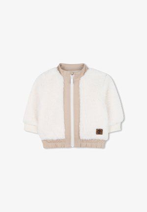 Veste en fausse fourrure crème avec des panneaux en tissu beige. Dotée d'une fermeture éclair blanche, de poignets côtelés et d'une taille élastique. Patch du logo Timberland sur le devant.