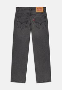 Jeans de mezclilla gris con corte recto, que presentan un parche de cuero en la parte trasera y dos bolsillos traseros con detalles de costura distintivos.