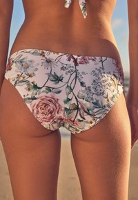 Cvetni bikini spodnji del z belo podlago in večbarvnimi vzorci rož in modrih cvetov. Mehka tkanina z gladko teksturo.