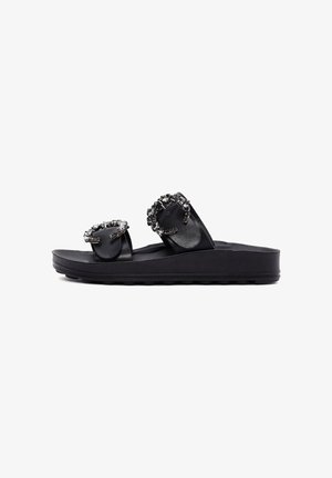 Sandalia tipo slide negra con dos tiras, cada una con una gran hebilla decorativa con piedras, sobre una suela gruesa.