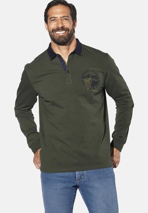 Long-sleeve polo shirt in dark green cotton with a navy collar. Features chest graphic and a relaxed fit. Worn with blue jeans.