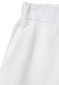 Witte stof met een textuur op het oppervlak, voorzien van een geplooide elastische tailleband. Het materiaal lijkt zacht en lichtgewicht te zijn.