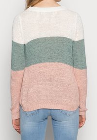 Pull en tricot avec des rayures pastel : blanc, turquoise et rose clair. Encolure arrondie, coupe décontractée et poignets et ourlet côtelés. Tissage texturé.