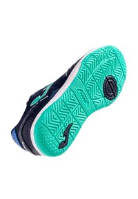 Suela de zapatilla deportiva con una parte inferior verde de goma y un patrón texturizado, además de acentos en negro. En el costado se muestra un logo azul y detalles.