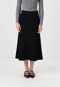 Musta ribbed midi -hame, jossa on istuva vyötärö. Yhdistetty harmaaseen pitkähihaiseen nappitoppiin ja mustiin kärkitossuihin, joissa on soljet.