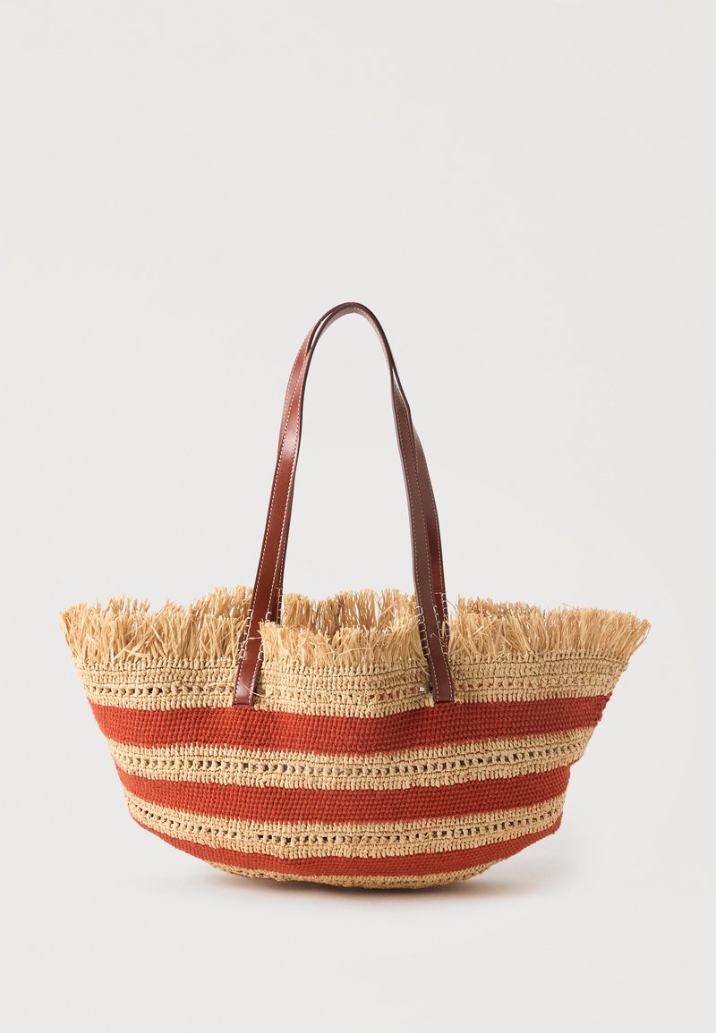 Sac cabas en paille tressée avec des rayures horizontales orange, bord supérieur à franges et deux bretelles en cuir marron.