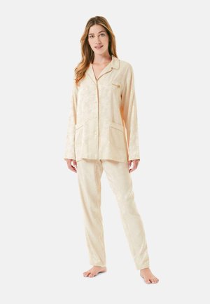 Conjunto de pijama beige que incluye una camisa con botones y cuello, y dos bolsillos, además de pantalones a juego con una sutil textura floral.