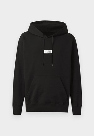 Haut à capuche noir en coton, avec une poche kangourou à l'avant, une capuche à cordon de serrage et une petite étiquette blanche sur la poitrine.