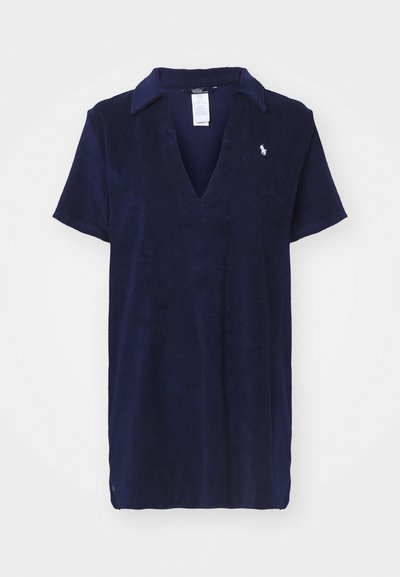 Polo de cor azul-marinho, de mangas curtas, com decote em forma de v, textura macia, apresentando um pequeno logotipo no peito. Estilo limpo e casual.