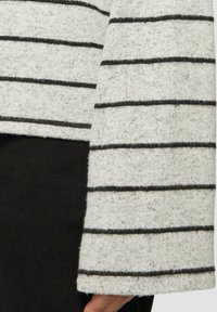 Grijze trui met zwarte horizontale strepen, met een zachte textuur en een recht afgesneden mouwzoom. Draag over een zwarte stof.