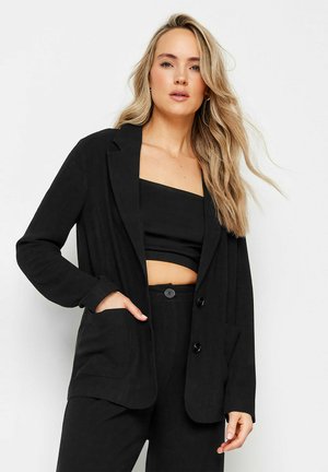 Blazer noir au design ajusté, doté de deux poches avant, de deux boutons et d'une texture de tissu léger, associé à un haut et un pantalon assortis.