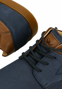 Scarpe in pelle blu navy con accenti marroni; punta rotonda e superficie testurizzata; lacci neri; etichetta con marchio vicino alla linguetta.