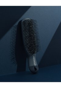 Svart hårbørste med bred paddle, fleksible børster og et teksturert håndtak. Har ordet "ARISTOCRAT" på siden.