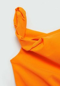 Helles orange ärmelloses Top mit einem gedrehten Stoffknotendetail an einer Schulter, dargestellt vor einem schlichten weißen Hintergrund.
