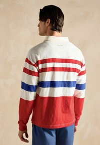 Pikend varrukatega polo särk, millel on punased, valged ja sinised triibud. Omab kraega kaelust ja brändinime "JOULES" seljal. Puuvillane kangas.