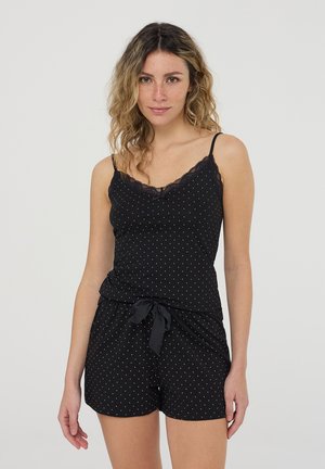 Completo pigiama nero con pois bianchi, composto da un canottiera con pizzo e pantaloni corti con un fiocco frontale. Realizzato in tessuto morbido.