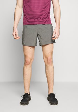 Grijze sportshorts met een elastische tailleband, gecombineerd met een bordeauxrode shirt met korte mouwen. Schoenen zijn zwart met een gestructureerd ontwerp.