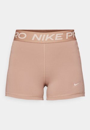 Nike Pro shorts, light tan, elastic waistband with "NIKE PRO" in beige, smooth textured fabric, fitted design, minimal stitching detail.