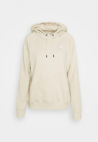 Světle béžová mikina s klokaní kapsou, kapucí se stahovacími šňůrkami a bílým logem Nike na hrudi. Měkká látka s hladkým povrchem.