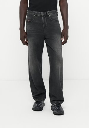 Jeans negros con un ajuste relajado, que presentan un lavado desgastado, diseño de cinco bolsillos y cinturilla con pasadores. Tela de mezclilla texturizada con costuras sutiles.