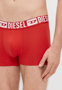 Punased bokserpüksid valge "DIESEL" logoga vöökohal, valmistatud siledast kangast, tiheda istuvusega ja mugavuse tagamiseks lamedate õmblustega.