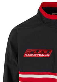 Veste de course noire avec col rouge et bandes rouges et blanches, avec un écusson rouge et noir portant l'inscription "FUBU Racing Team 05" sur la poitrine.