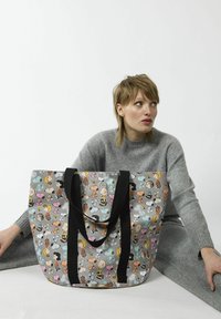 Tote bag mit grauem Hintergrund, dekoriert mit bunten Cartoon-Figuren. Schwarze Griffgurte, große Größe und weiche Textur.
