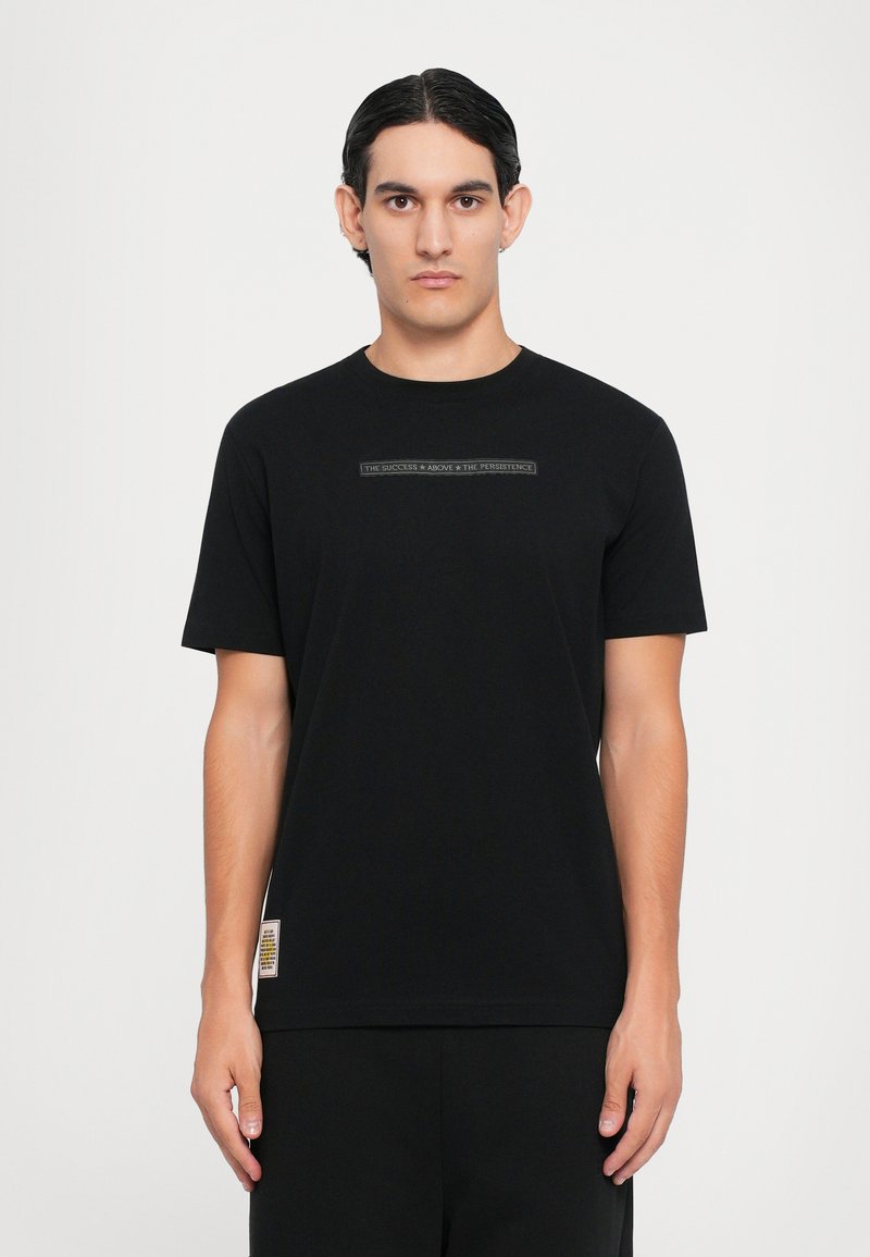 Black t-shirt in soft cotton, featuring short sleeves and a crew neck. Centered text graphic across the chest, with a brand label at the hem.