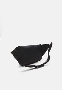 Sort nylon crossbody taske med polstret tekstur, vinklet design, justerbar rem og spænde lukning. Kompakt og struktureret form.